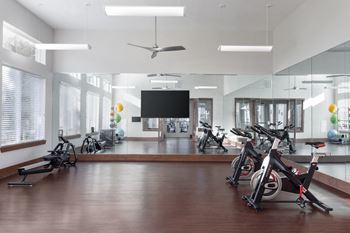 a workout room with exercise bikes and a tv